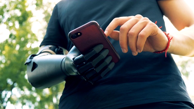 一个戴着现代假肢的男人看着他的手机。4 k。视频下载