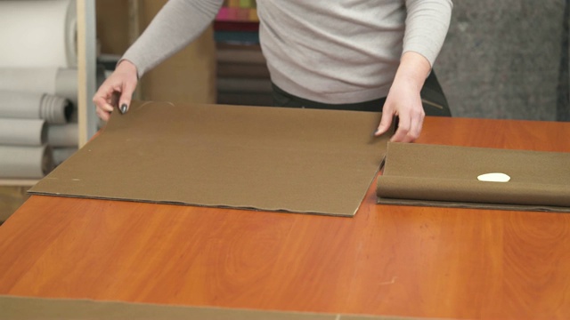 一个裁缝裁剪一个高质量的棕色织物，使用专业剪刀和方形切割织物块视频素材