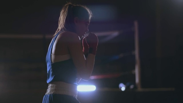 女子拳击训练在暗室与背光慢动作侧视图。替身拍摄视频素材