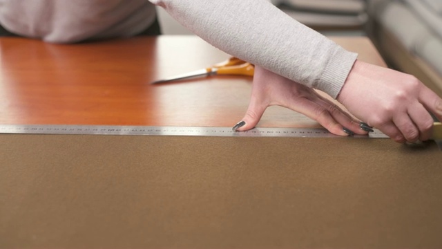 一个裁缝用尺子在织物上用粉笔做图案的演示视频。视频素材