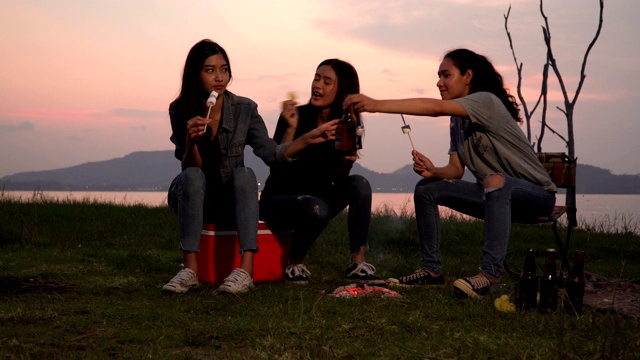 三个女人在日落时分露营时吃着棉花糖和零食视频素材
