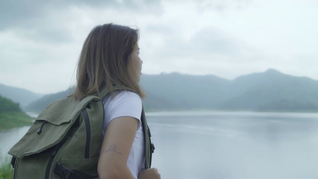 徒步女背包客徒步冒险感觉自由行走在森林附近的湖在雨天。生活方式女性旅游放松的概念。视频素材