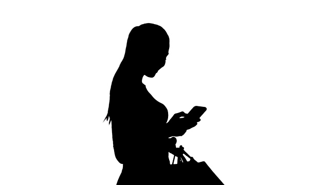 剪影美丽的年轻女子使用手机行走和拿着购物袋视频素材