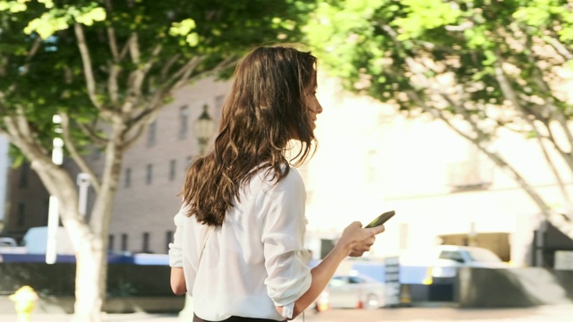 商务女性使用智能手机和喝咖啡在路上视频素材