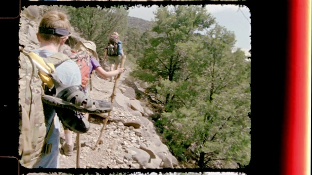 在新墨西哥州的大北国家纪念碑，老式电影摄影机跟随家庭背包客沿着岩石小径徒步旅行。视频下载