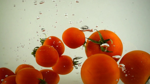 西红柿和圣女果落在水中。缓慢的运动。视频素材