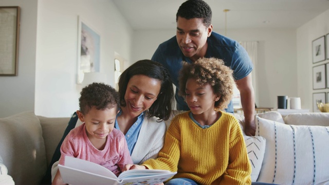 年轻的混血儿妈妈和她的两个孩子一起看书，爸爸看着他们视频素材