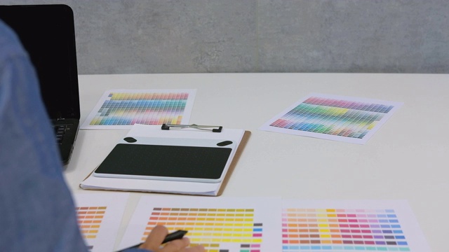 室内设计师在办公室绘图板上作画。艺术家与电脑和选择颜色从样本目录调色板指南在工作场所。摄影师润饰照片。设计创意创意概念视频素材