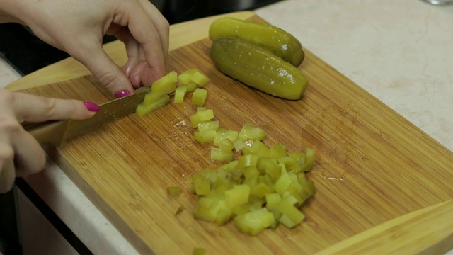 女主妇在厨房里用手把腌黄瓜切成片视频素材