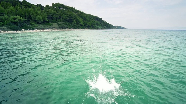 运动跳跃男孩使后空翻在海水绿松石视频素材