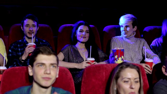 一群青少年朋友在电影院看电影，吃爆米花。视频素材