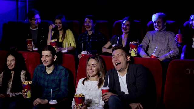 年轻的朋友们坐在电影院，吃着爆米花，喝着饮料，看一部喜剧电影。视频素材