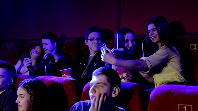 一群兴高采烈的青少年在电影院后排自拍。视频素材