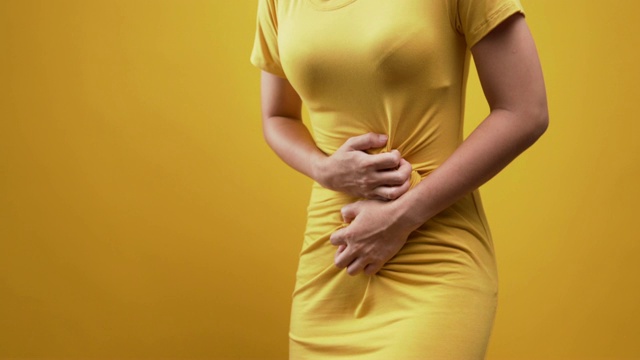 女人胃痛孤立在黄色背景视频下载