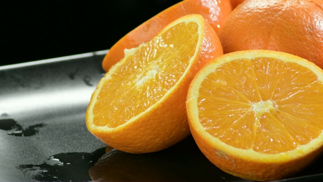 橙子切成两半，放在黑色托盘上旋转视频下载