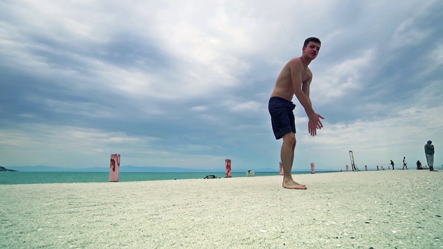 全身像跑酷男子跳高在海滩上表演后空翻，慢动作视频素材