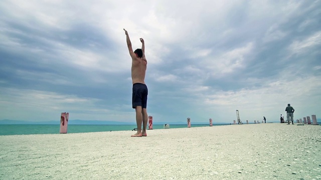 全身像跑酷男子跳高在海滩上表演后空翻视频素材