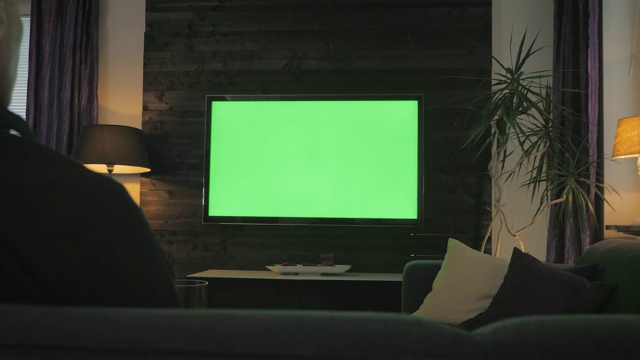 绿屏人在客厅看电视。过肩射击。视频素材