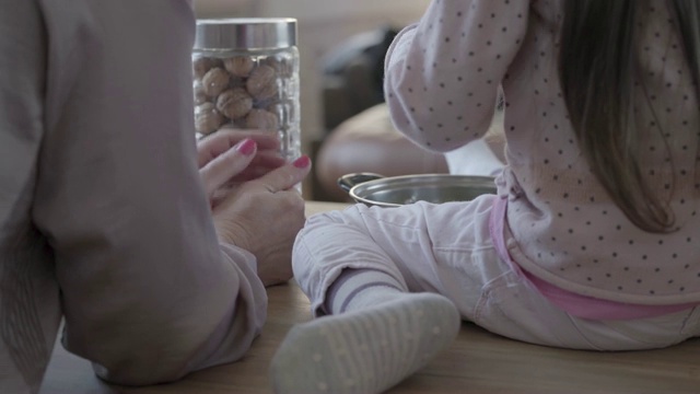 女人和小孩坐在厨房的桌子上，母亲教女儿如何做饭的背影。视频素材