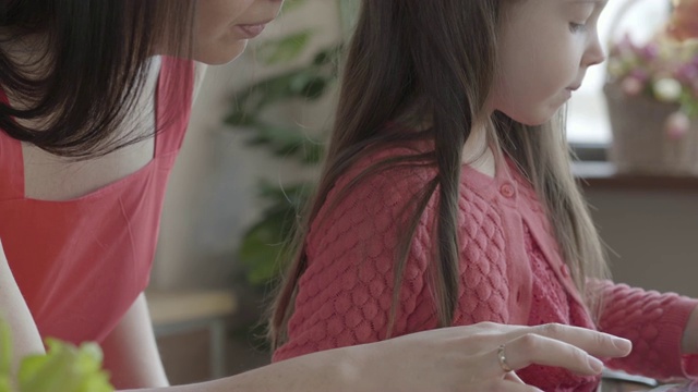 一个面目全非的女人和她的小女儿在平板电脑上玩。视频素材
