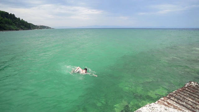 快乐的男孩在碧绿的海水里游泳，慢镜头，慢镜头视频素材
