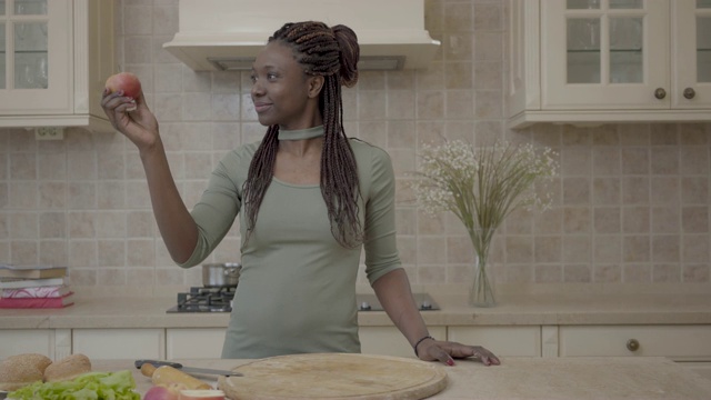 自信的非洲裔美国年轻女子微笑着准备馅饼，微笑着看着苹果视频素材