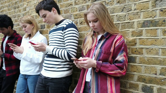 一群青少年朋友专注于自己的智能手机在社交媒体上发短信视频素材