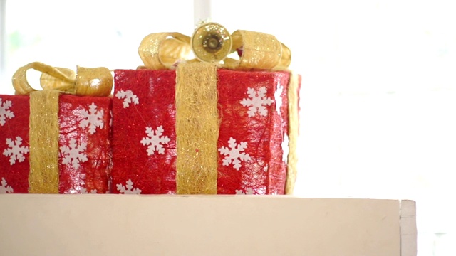 镜头:圣诞节的时候，木桌上放着两个红色的礼盒，上面有金色的蝴蝶结。视频素材