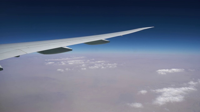 飞机在白云之上的高空飞行。飞机的机翼在窗户上。空中飞行视频素材