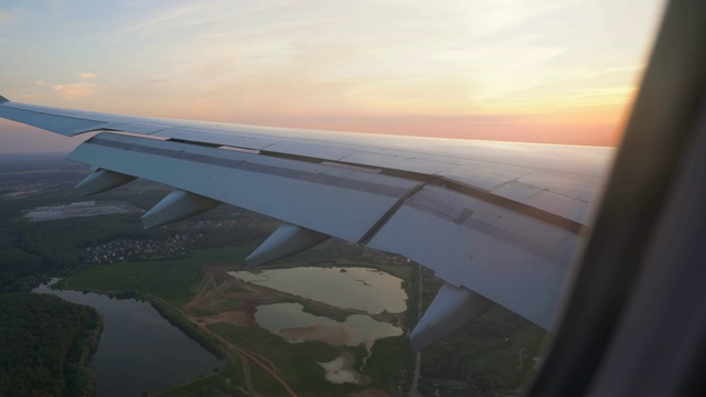 从飞机窗口看到的日落。阳光下的翅膀。空中飞行视频素材