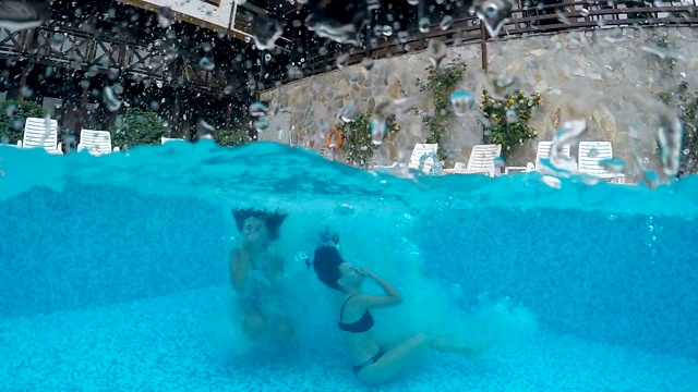 两个快乐的女孩微笑着跳进泳池，gopro圆顶电影慢动作拍摄，慢动作视频素材