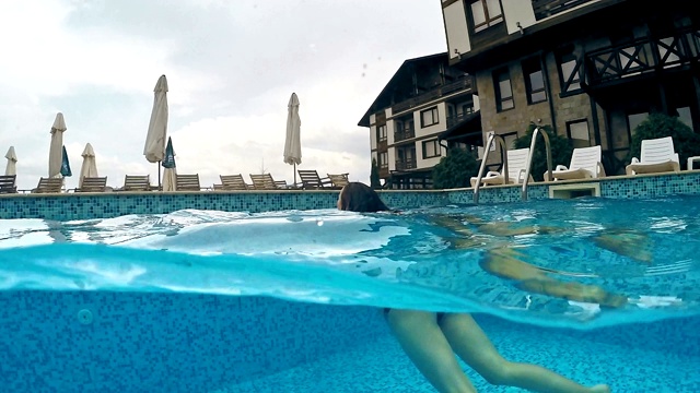 时尚模特少年游泳在豪华别墅游泳池的后视图，gopro圆顶半水下视图，慢动作视频素材