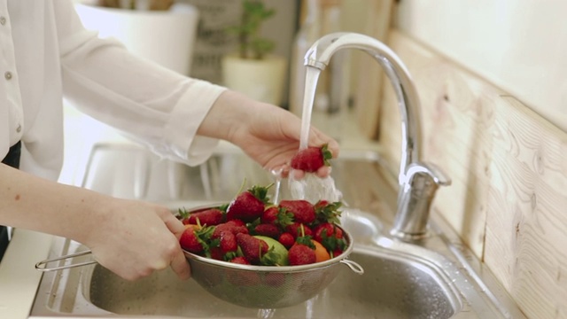 一个女人在厨房水龙头下洗草莓视频下载