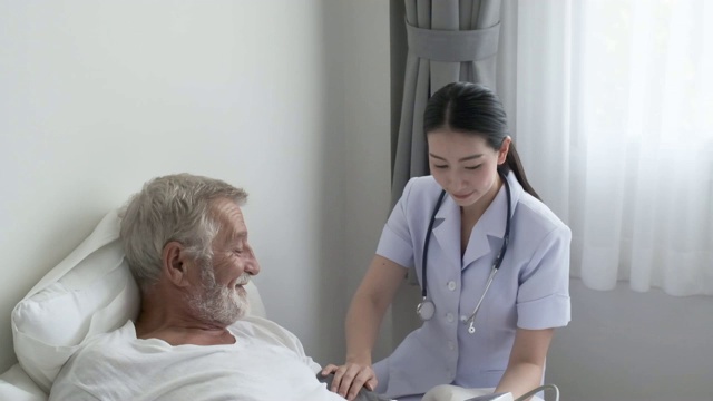 爷爷或老人躺在床上，护士来到老人身边，微笑着做健康检查和讨论视频素材