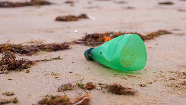 塑料瓶的一部分被带到沙滩上。视频素材