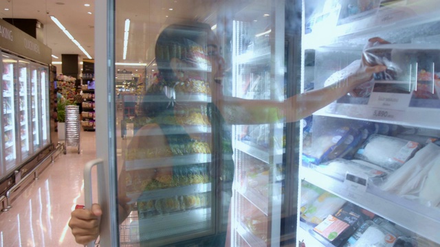 年轻美丽的亚洲女人购买新鲜冷冻海鲜在杂货店超市。视频下载
