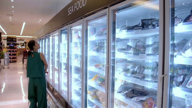 年轻美丽的亚洲女人购买新鲜冷冻海鲜在杂货店超市。视频素材
