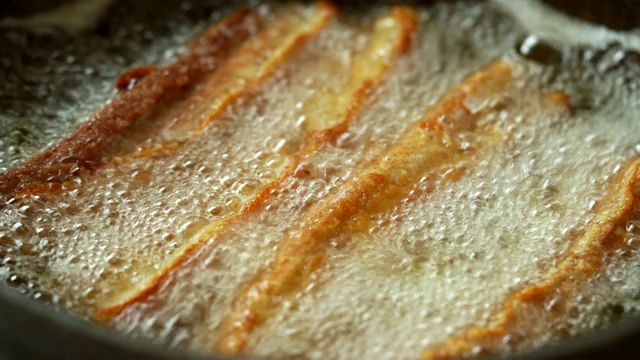 4K视频选择聚焦稳定近距离微距拍摄新鲜的自制油炸酥脆的猪肉腩在沸腾的棕榈油在煎锅。视频素材