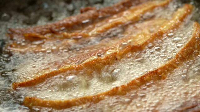 4K视频选择聚焦稳定近距离微距拍摄新鲜的自制油炸酥脆的猪肉腩在沸腾的棕榈油在煎锅。视频素材