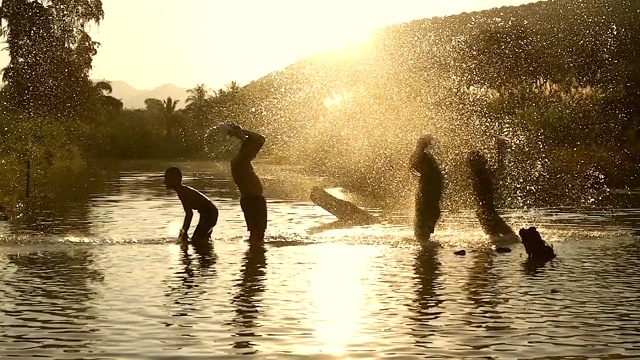 亚洲男孩玩他的水牛在河与溅水一起。(缓慢)视频素材