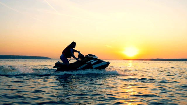 一个男人驾驶着一艘快艇穿过夕阳下的水景视频素材
