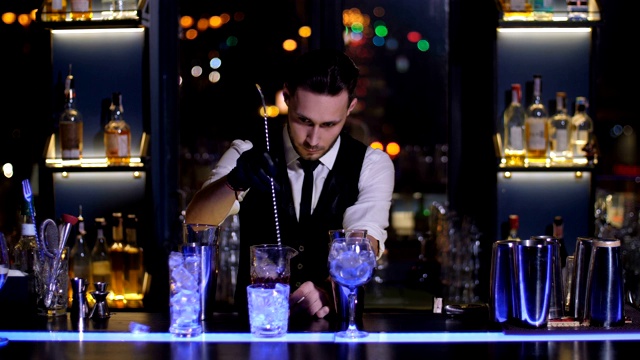 调酒师在调酒杯中搅拌冰块和酒精视频下载