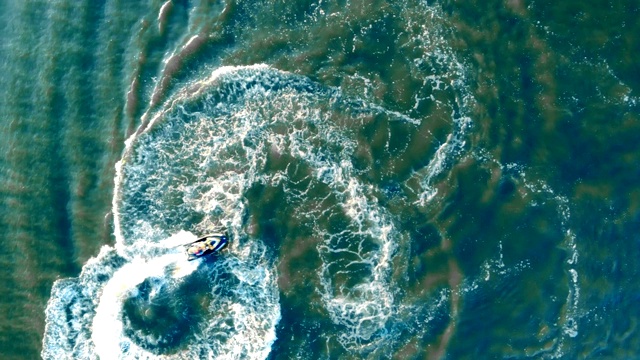 从上面看，一辆水上摩托车驶过海面后，溅起了水花和波浪视频下载