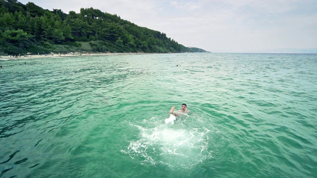 快乐的男孩在碧绿的海水里游泳，慢镜头视频素材