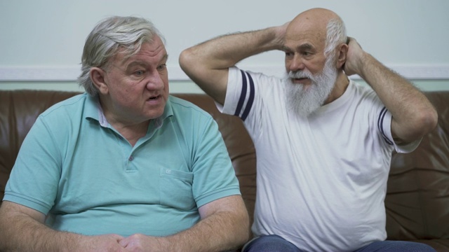 两个年长的男人坐在皮沙发上的肖像。视频下载