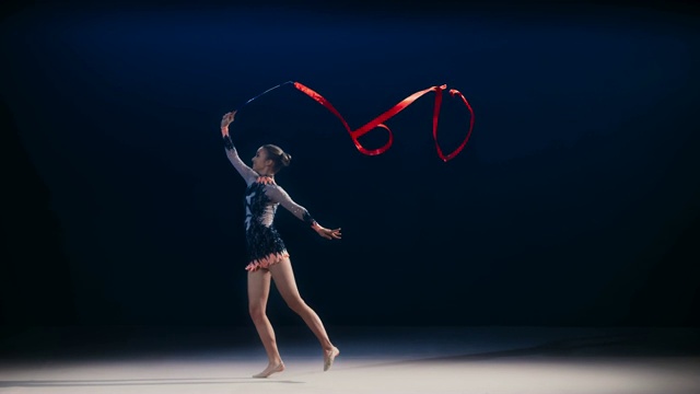 艺术体操运动员旋转红丝带并表演跳跃动作视频素材