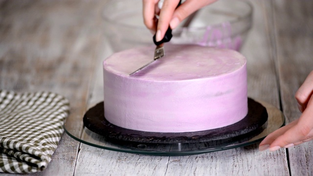 用紫色奶油盖装饰蛋糕的过程。糖果商使用糕点抹刀等量饼干奶油。视频下载