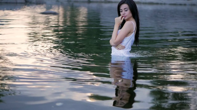 性感的黑发长发女孩站在水里。缓慢的运动。视频下载