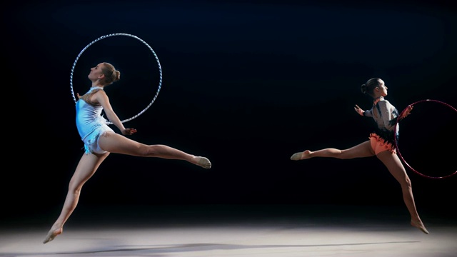 两名艺术体操运动员相对着做一个带环的劈叉跳跃视频素材