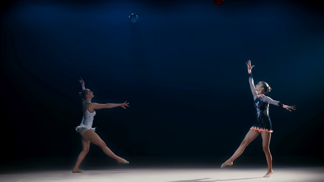 两名艺术体操运动员向相反的方向移动，并将球高高地抛向空中视频素材